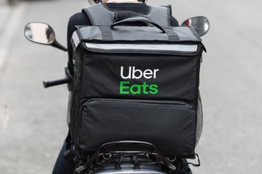 Osaka, Japonya - Ekim 2019: Uber Eats bisikletçisi Roppongi caddesinde bisiklet sürüyor