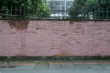 Mimari çit, tuğla duvar ve parktaki ağaçlar 