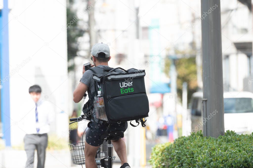 Osaka, Japan - October , 2019 :  Uber Eats rider cycling in the street of Roppongi