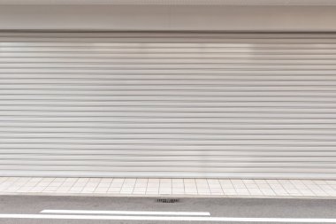 Fabrikada, depoda, garajda ve endüstriyel depoda kullanılan otomatik metal paten kapısının yakın çekimi. Bükülebilir ve katlanabilir metal levha yer tasarrufu sunuyor ve kentsel ve kırsal hissi sağlıyor