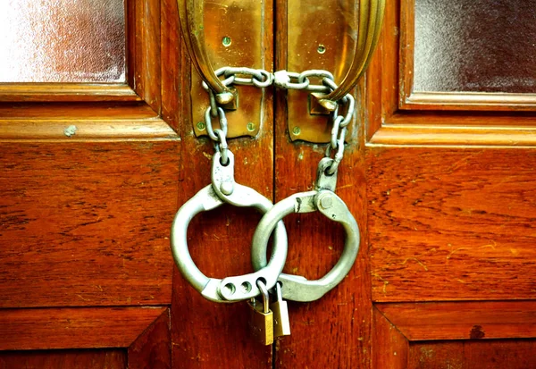 Set of handcuffs locking an old door