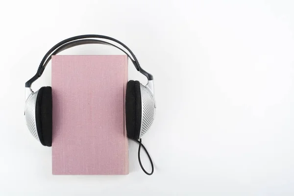 Fones Ouvido Sobre Livro Hardback Rosa Fundo Branco — Fotografia de Stock