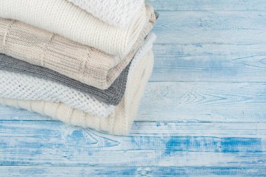 Örgü yün kazaklar. Mavi ahşap arka planda örülmüş kışlık giysiler, kazaklar, örgü giysiler, metin için yer