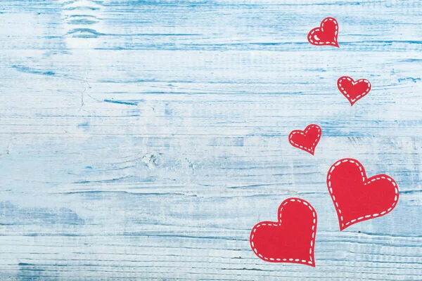 Red paper hearts on a blue wooden background. Valentine\'s Day. Copy space. Top view.