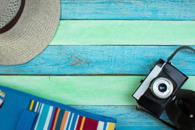 Şapka, kamera, çanta, gözlük, yaz için ahşap arka planda güneş kremi. Üst görünüm ve kopyalama alanı