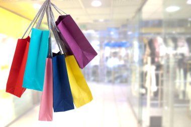 Alışveriş merkezi arka plan üzerinde renkli kağıt torba tutarak kırpma el.