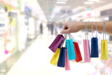 Alışveriş merkezi arka plan üzerinde renkli kağıt torba tutarak kırpma el.