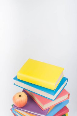 Renkli gerçek kitap yığını, beyaz arka plan, kısmi görünümü üzerinde elma. Okul hazırlıkları kopya alanı. Eğitim