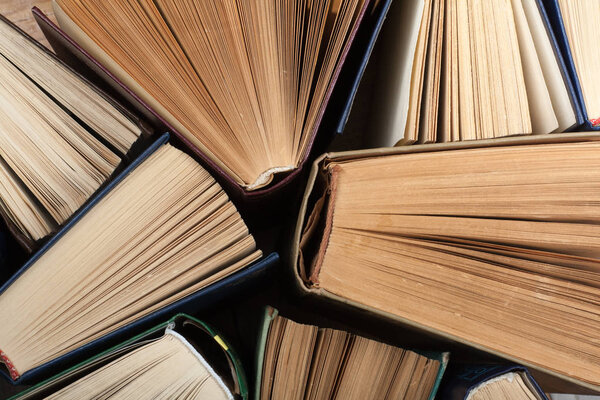Old and used hardback books or text books seen from above. Books and reading are essential for self improvement, gaining knowledge and success in our careers, business and personal lives