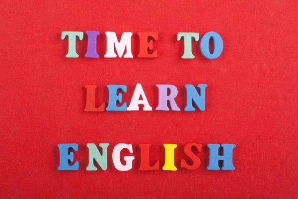 TIME TO LEARN ENGLISH word on red background composed from colorful abc alphabet block wooden letters, copy space for ad text. Learning english concept