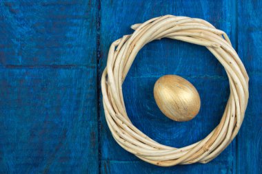 Mutlu Paskalyalar. Tahta masa arkasında izole edilmiş yumurtalar... Toplar, sarmaşıklardan örülmüş çelenkler. Uzayı metin için kopyala. Üst görünüm