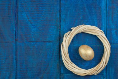 Mutlu Paskalyalar. Tahta masa arkasında izole edilmiş yumurtalar... Toplar, sarmaşıklardan örülmüş çelenkler. Uzayı metin için kopyala. Üst görünüm