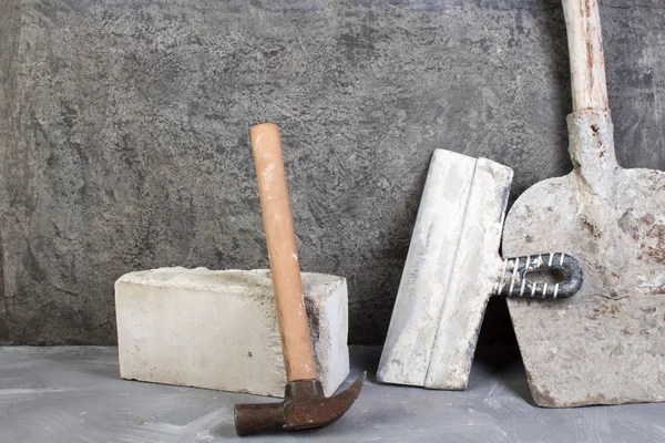 bricks, hammer, putty knife, old, dirty shovel on the gray concrete background. Copy space. Top view