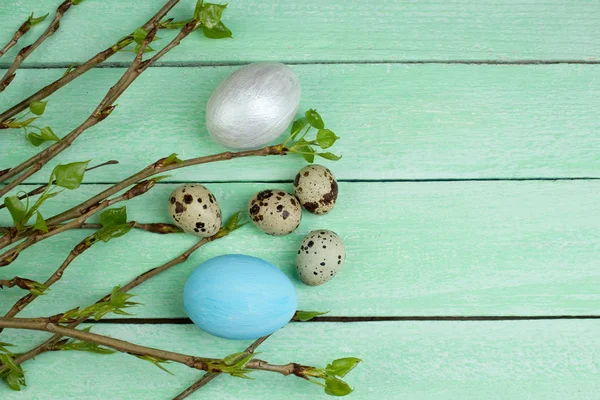 Ahşap masa arkasında yaprakları olan Paskalya yumurtaları ve dalları. Üst Manzara. Metin için alanı kopyala
