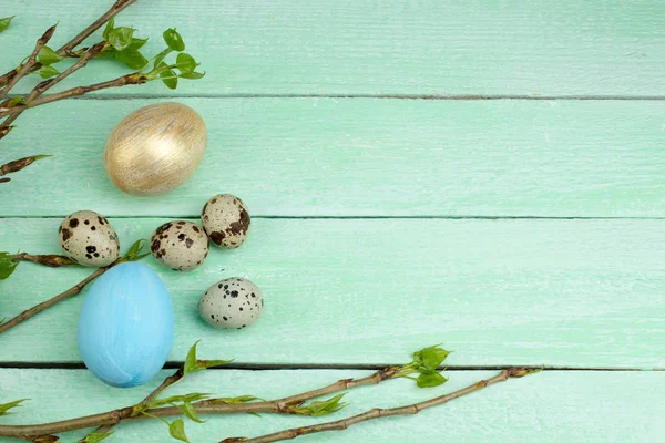 Ahşap masa arkasında yaprakları olan Paskalya yumurtaları ve dalları. Üst Manzara. Metin için alanı kopyala