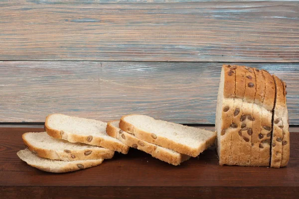 Many mixed breads and rolls of baked bread on wooden table background