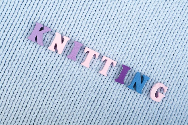 Örgü. Mavi örme kumaş dokusu. ABC alfabesi harfleri oluşan kelime