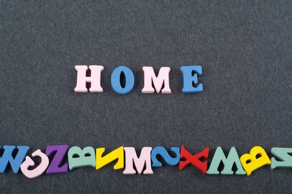 HOME word on black board background composed from colorful abc alphabet block wooden letters, copy space for ad text. Learning english concept