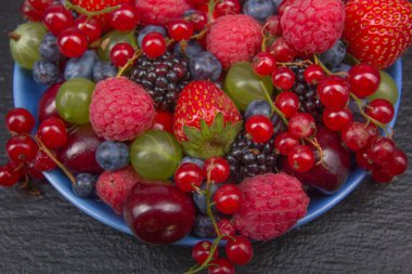 Bir kase rustik ahşap masa üzerinde çeşitli yaz taze çilek. Antioksidan, detoks diyet, organik meyve