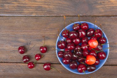 Çeşitli taze kiraz bir kase rustik ahşap masa üzerinde yaz. Antioksidan, detoks diyet, organik meyve.