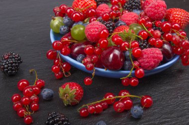 Bir kase rustik ahşap masa üzerinde çeşitli yaz taze çilek. Antioksidan, detoks diyet, organik meyve