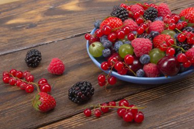 Bir kase rustik ahşap masa üzerinde çeşitli yaz taze çilek. Antioksidan, detoks diyet, organik meyve