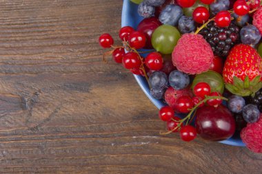 Bir kase rustik ahşap masa üzerinde çeşitli yaz taze çilek. Antioksidan, detoks diyet, organik meyve