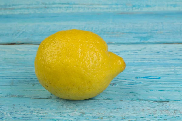 One lemon isolated on blue wooden background. Tropical fruit. Flat lay, top view