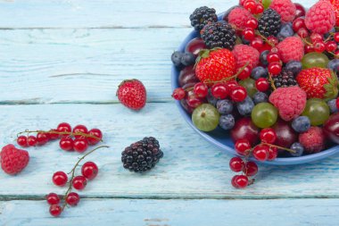 Bir kase rustik ahşap masa üzerinde çeşitli yaz taze çilek. Antioksidan, detoks diyet, organik meyve