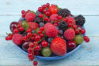 Bir kase rustik ahşap masa üzerinde çeşitli yaz taze çilek. Antioksidan, detoks diyet, organik meyve