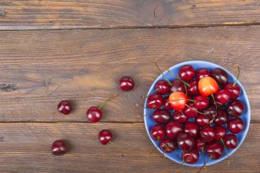 Çeşitli taze kiraz bir kase rustik ahşap masa üzerinde yaz. Antioksidan, detoks diyet, organik meyve.