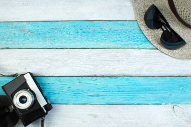 Şapka, kamera, çanta, gözlük, yaz için ahşap arka planda güneş kremi. Üst görünüm ve kopyalama alanı