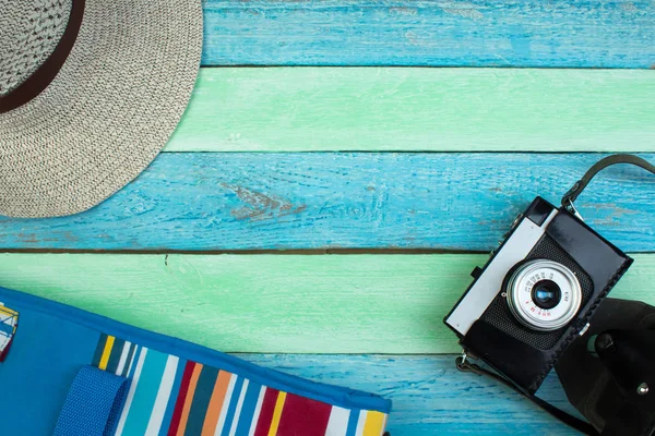 Şapka, kamera, çanta, gözlük, yaz için ahşap arka planda güneş kremi. Üst görünüm ve kopyalama alanı