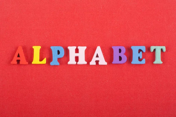 Parola ALPHABET su sfondo rosso composta da colorati alfabeto abc blocco lettere di legno, copiare spazio per il testo dell'annuncio. Imparare l'inglese concetto . — Foto Stock