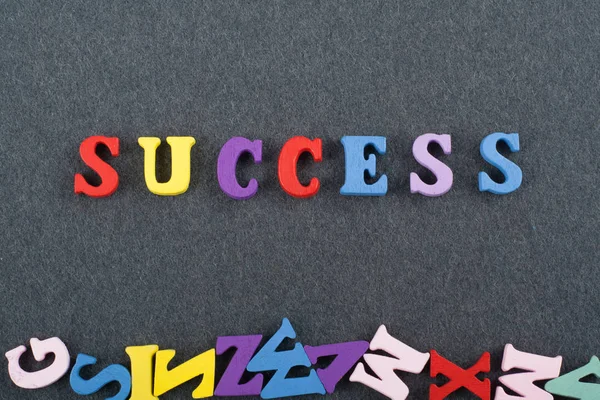 SUCCESS word on black board background composed from colorful abc alphabet block wooden letters, copy space for ad text. Learning english concept.