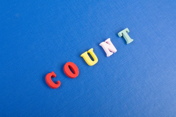 COUNT word on blue background composed from colorful abc alphabet block wooden letters, copy space for ad text. Learning english concept.