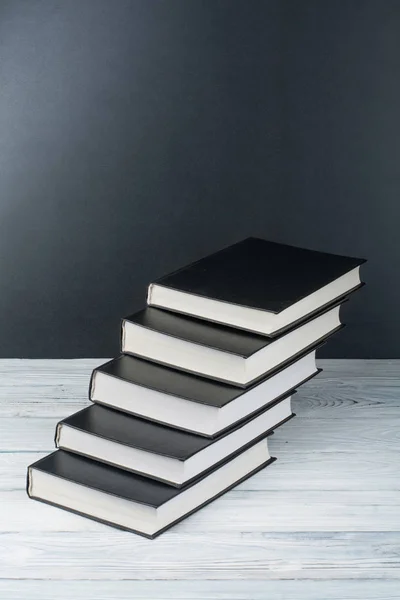 Open boeken over houten tafel, zwarte bord achtergrond. Terug naar school. Onderwijs bedrijfsconcept. — Stockfoto