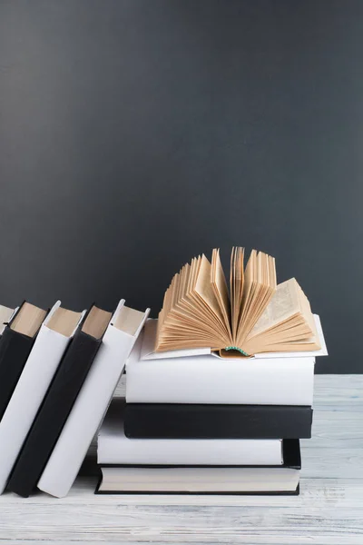 Libros abiertos sobre mesa de madera, fondo de pizarra negra. De vuelta a la escuela. Concepto de negocio educativo . —  Fotos de Stock