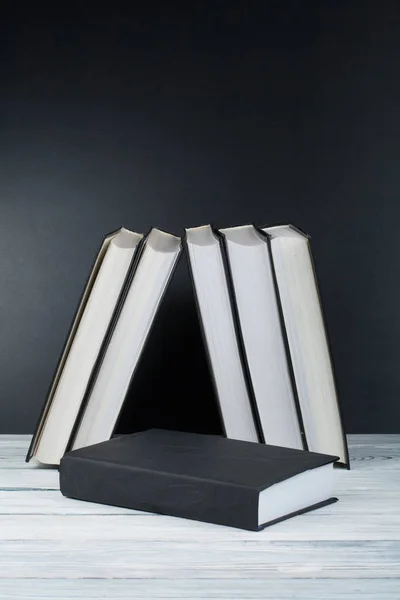 Open boeken over houten tafel, zwarte bord achtergrond. Terug naar school. Onderwijs bedrijfsconcept. — Stockfoto