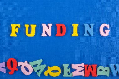 Renkli abc alfabe blok ahşap gelen mektuplar oluşan mavi arka plan üzerinde kelime finansman, reklam metin için yer kopyalayın. Öğrenme İngilizce kavramı