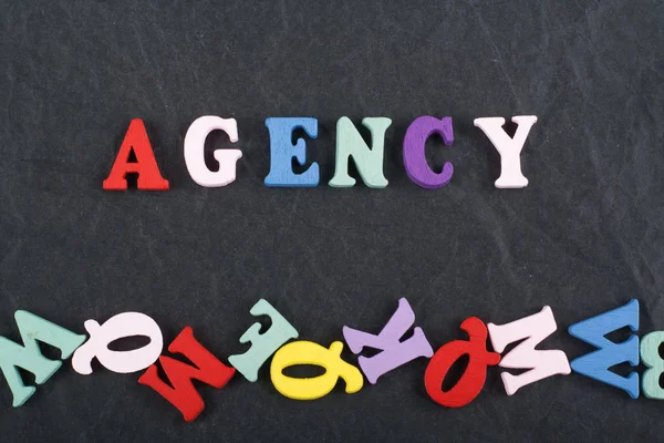AGENCY word on black board background composed from colorful abc alphabet block wooden letters, copy space for ad text. Learning english concept