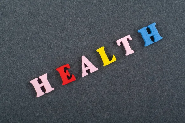 HEALTH word on black board background composed from colorful abc alphabet block wooden letters, copy space for ad text. Learning english concept
