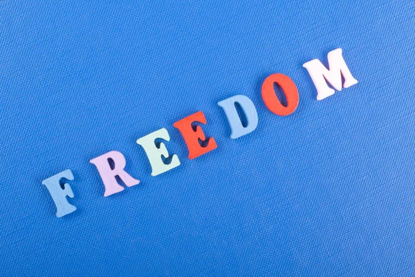 FREEDOM word on blue background composed from colorful abc alphabet block wooden letters, copy space for ad text. Learning english concept