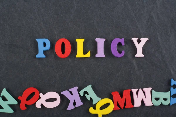 POLICY word on black board background composed from colorful abc alphabet block wooden letters, copy space for ad text. Learning english concept