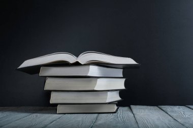 Ahşap masa, siyah tahta arka plan üzerine açık siyah ve beyaz kitaplar. Okula dönüş. Eğitim iş kavramı