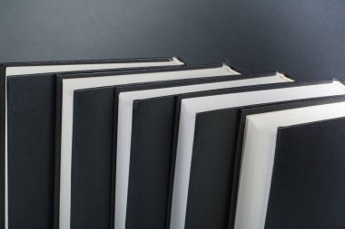 Ahşap masa, siyah tahta arka plan üzerine açık siyah ve beyaz kitaplar. Okula dönüş. Eğitim iş kavramı