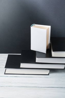 Ahşap masa, siyah tahta arka plan üzerine açık siyah ve beyaz kitaplar. Okula dönüş. Eğitim iş kavramı
