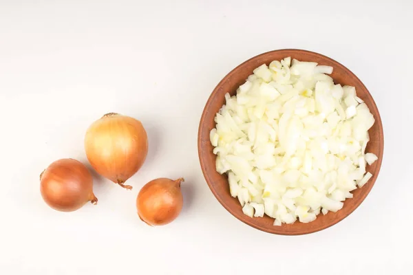 White onion cubes in ceramic bowl isolated on white background. Chopped fresh, raw Allium cepa, also bulb or common onion. Vegetable, ingredient and staple food.