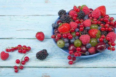 Bir kase rustik ahşap masa üzerinde çeşitli yaz taze çilek. Antioksidan, detoks diyet, organik meyve