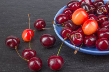 Çeşitli taze kiraz bir kase rustik ahşap masa üzerinde yaz. Antioksidan, detoks diyet, organik meyve